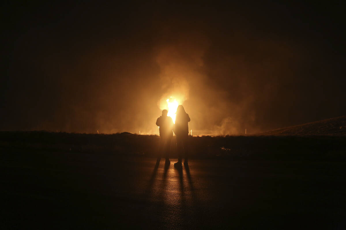 Two men look at flames after a natural gas pipeline explodes outside the city of Boroujen in th ...