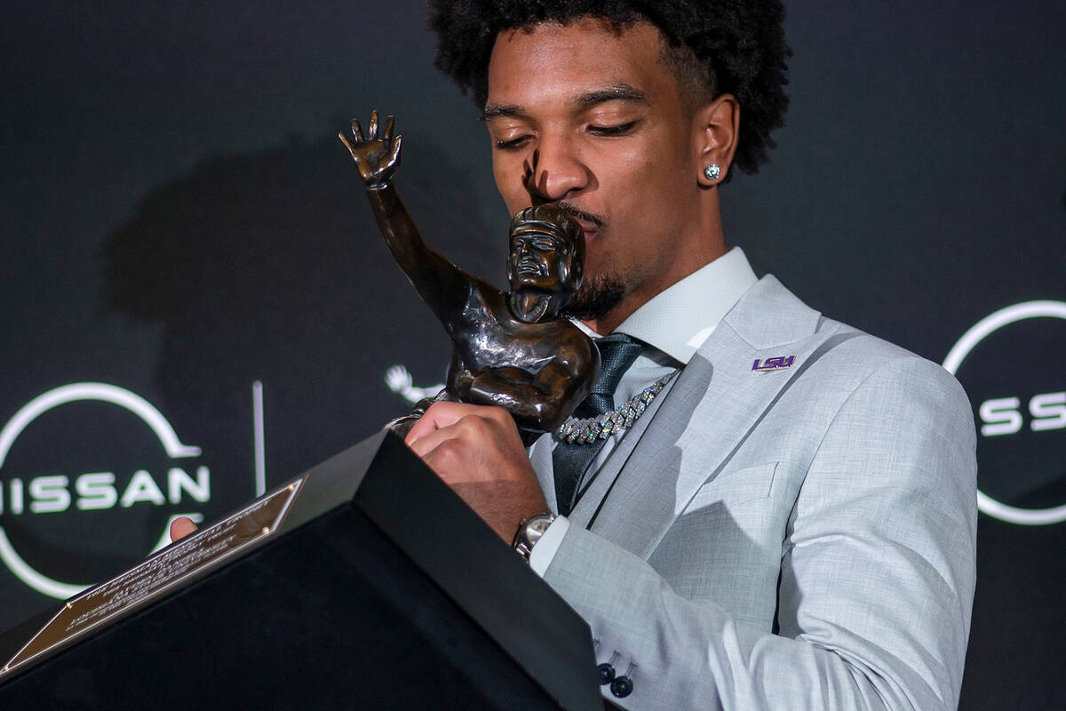 LSU quarterback Jayden Daniels kisses the Heisman Trophy during a news conference after winning ...