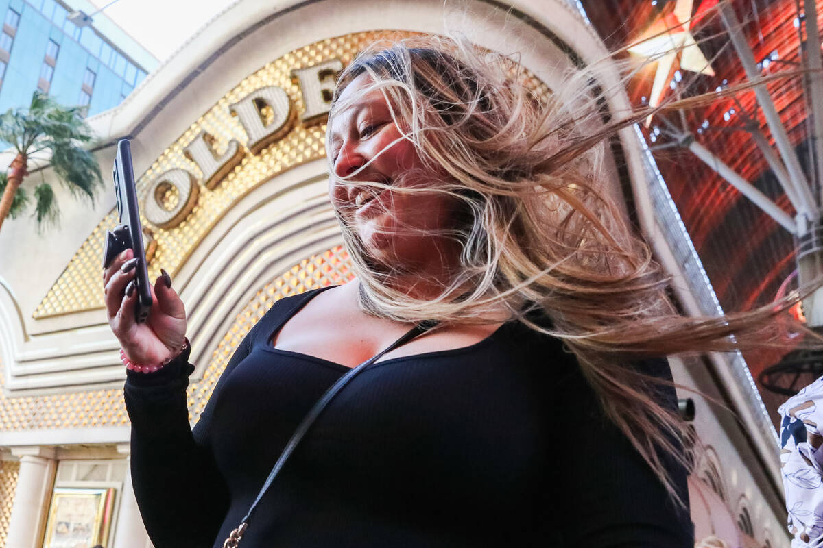 A tourist battles through the wind along Fremont Street on Monday, Nov. 6, 2023 in Las Vegas. ( ...