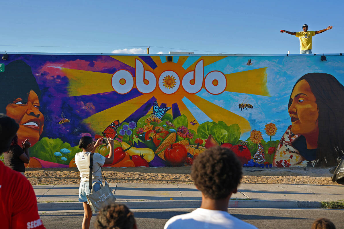 Muralist Malachi Williams, top/right, cheers after he unveils a flagship mural at the opening o ...