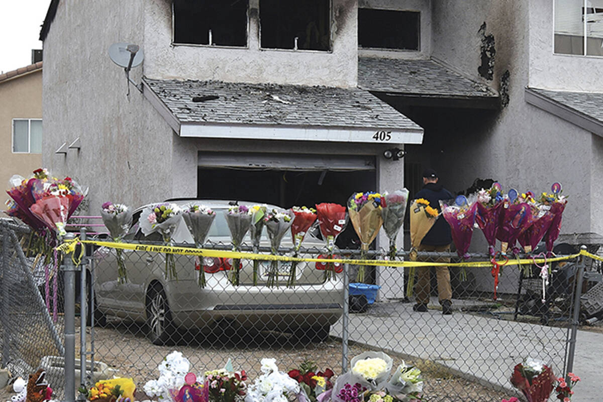 Flowers, stuffed animals and candles are placed on and along a chain-link fence in a makeshift ...