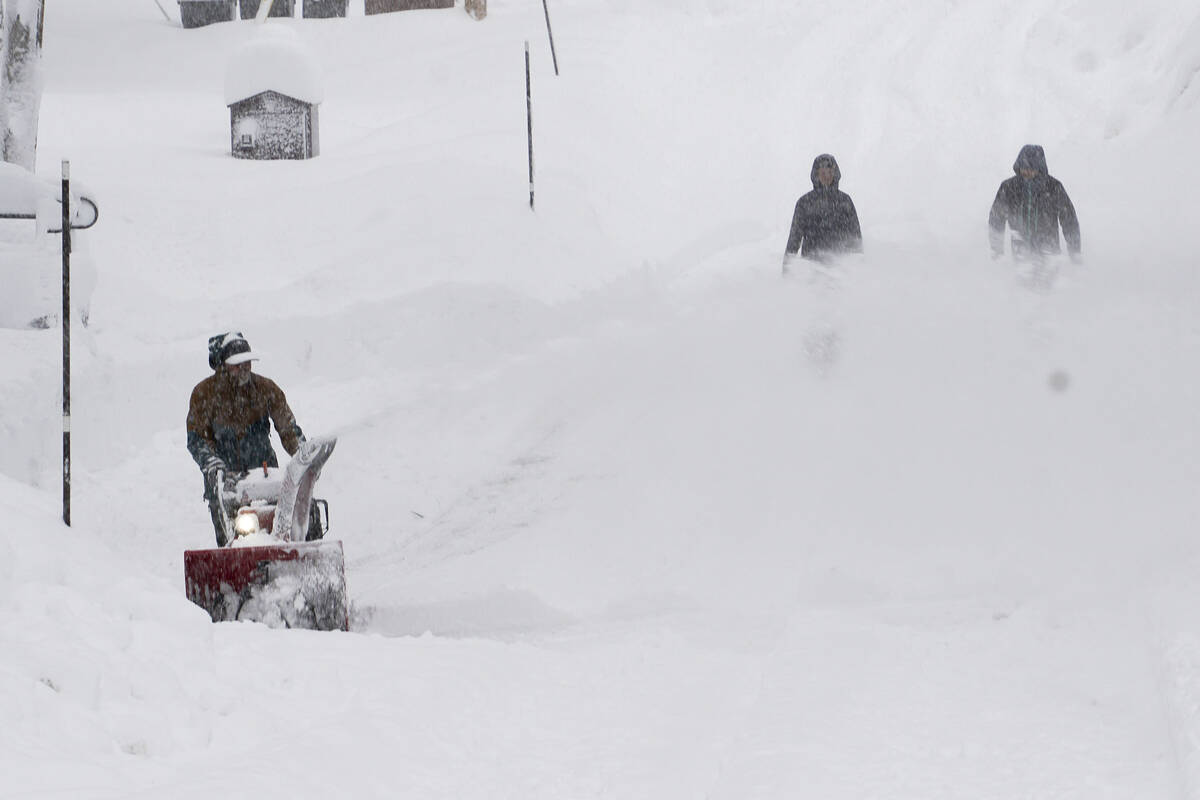 Residents clear snow as it piles up during a storm, Saturday, March 2, 2024, in Truckee, Calif. ...