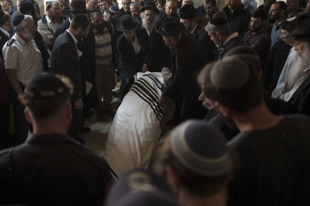The body of Yitzhak Zeiger is placed in his grave during his funeral at a cemetery in Jerusalem ...