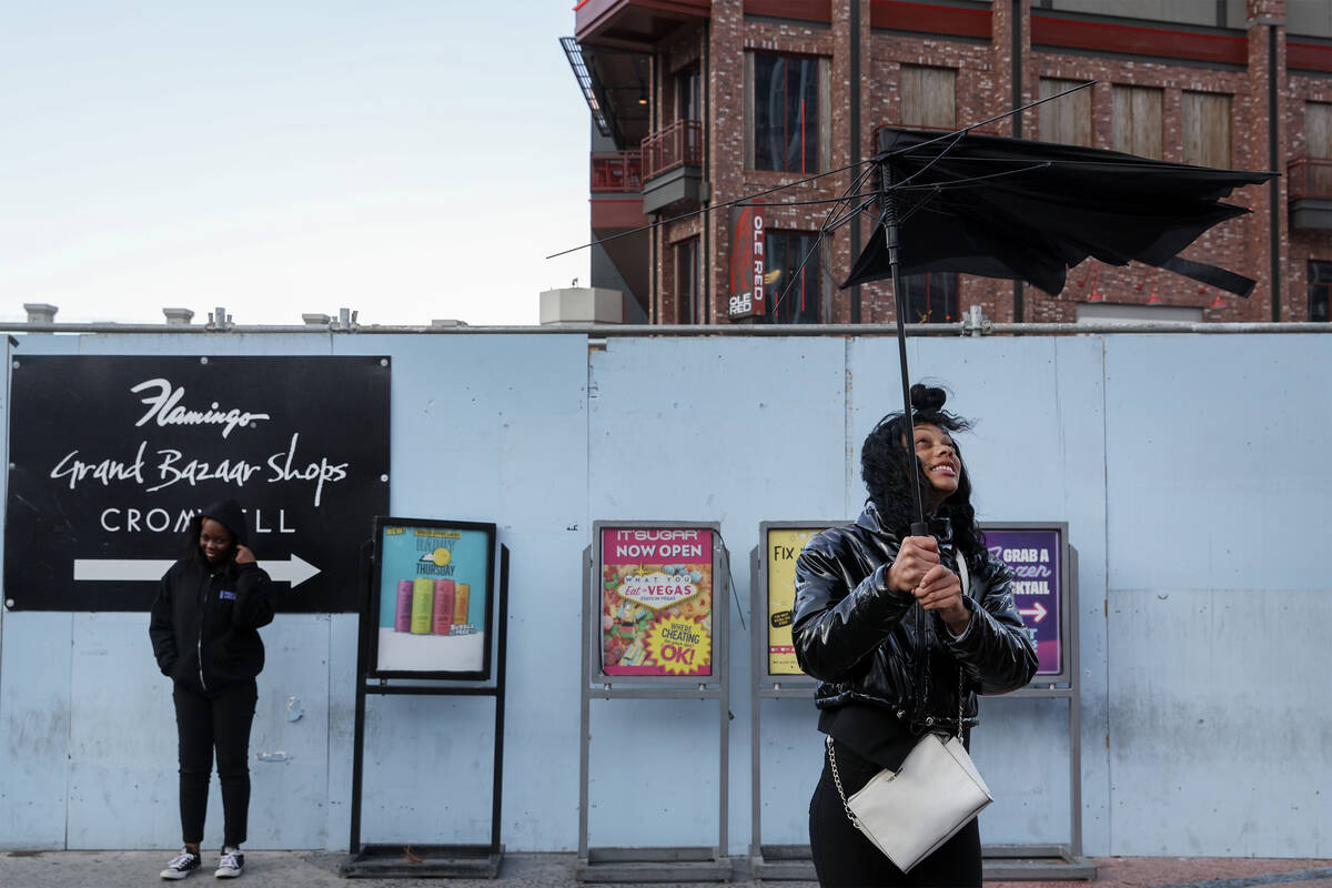 A visitor to the Las Vegas Strip struggles with a broken umbrella as a high wind warning is in ...