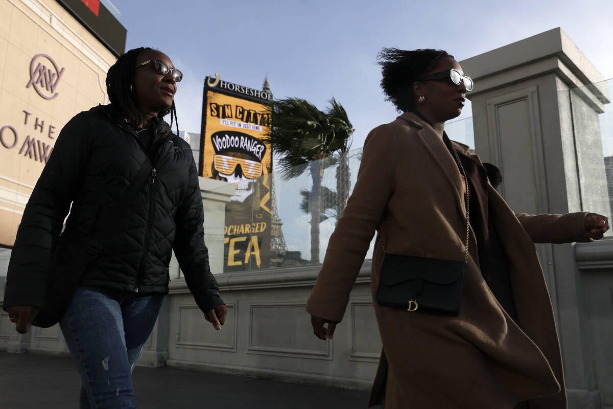 Visitors to the Las Vegas Strip traverse Las Vegas Boulevard as a high wind warning is in effec ...