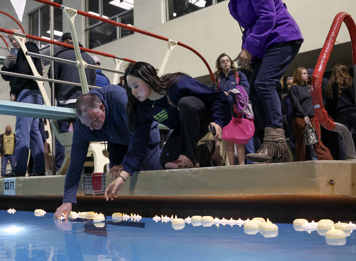 Loved ones of star swimmer Charlie Clark, 19, place candles in the water during a vigil at Hend ...