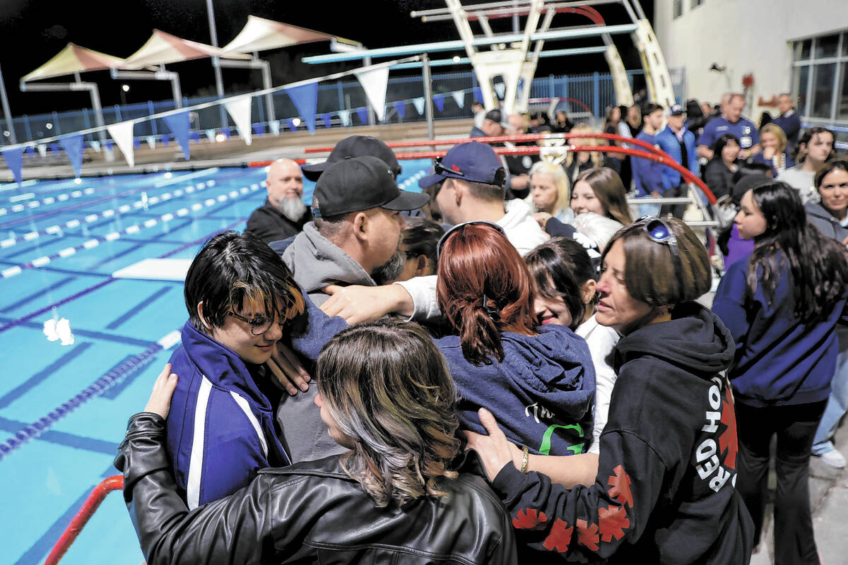 Loved ones of star swimmer Charlie Clark, 19, form a group hug during a vigil at Henderson Mult ...