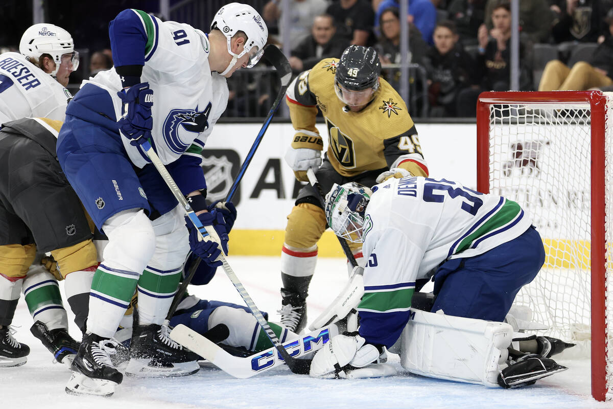 Golden Knights center Ivan Barbashev (49) battles at the net with Canucks defenseman Nikita Zad ...