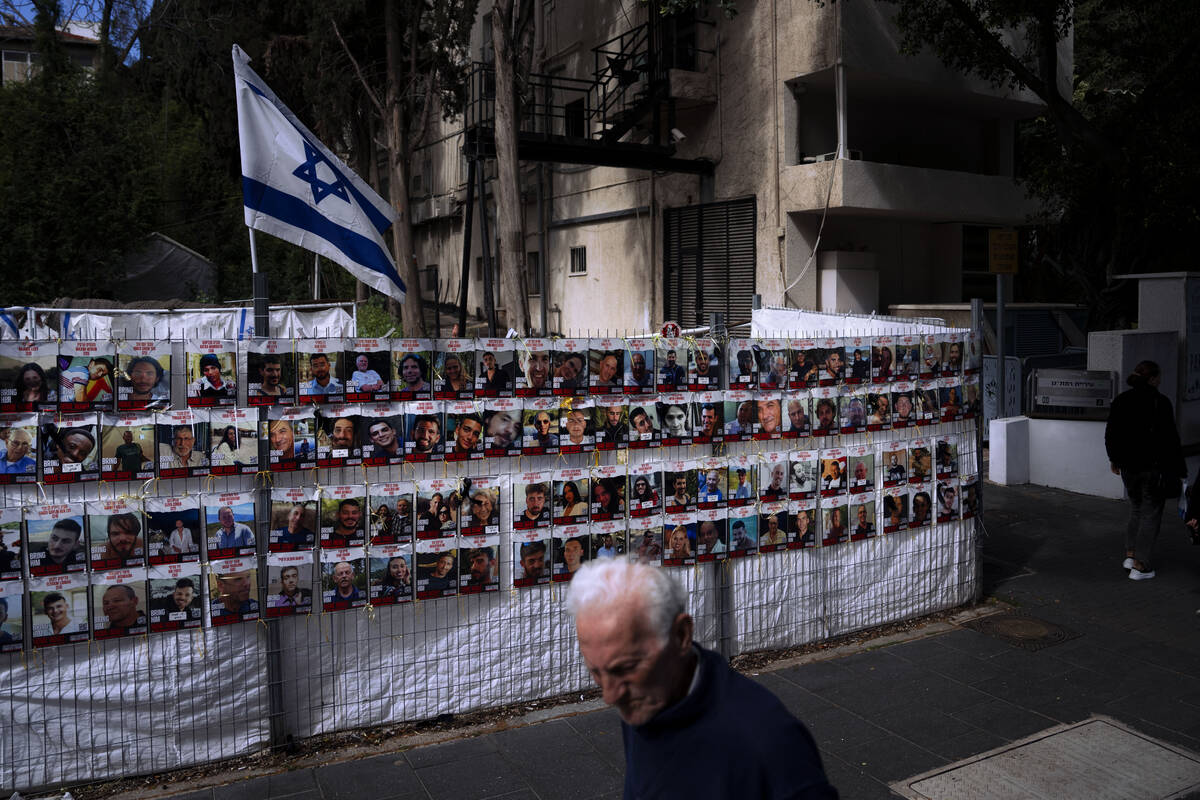 People pass by a fence with photographs of Israelis who are being held hostage in the Gaza Stri ...