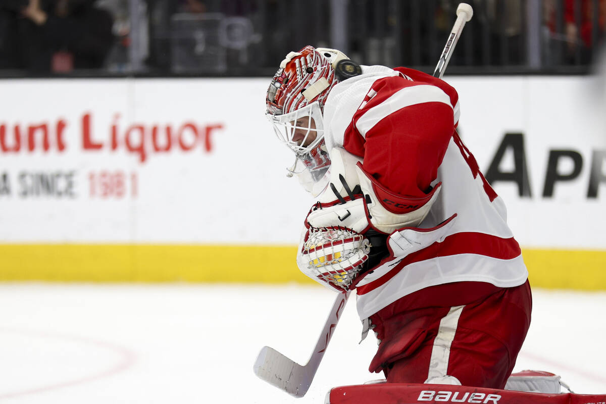 The puck slides past Red Wings goaltender James Reimer’s helmet as the Golden Knights sc ...