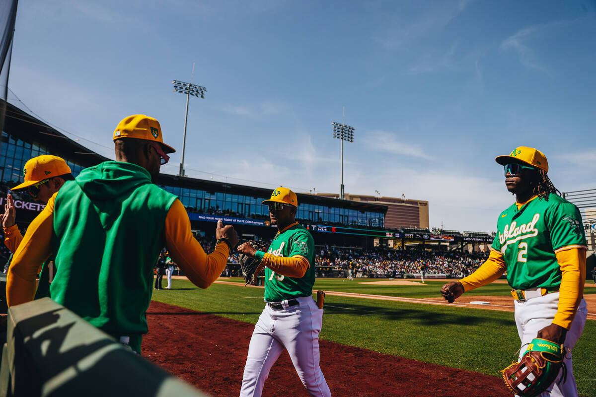 Oakland a’s players high five as they make their way into the dug out during a Big Leagu ...
