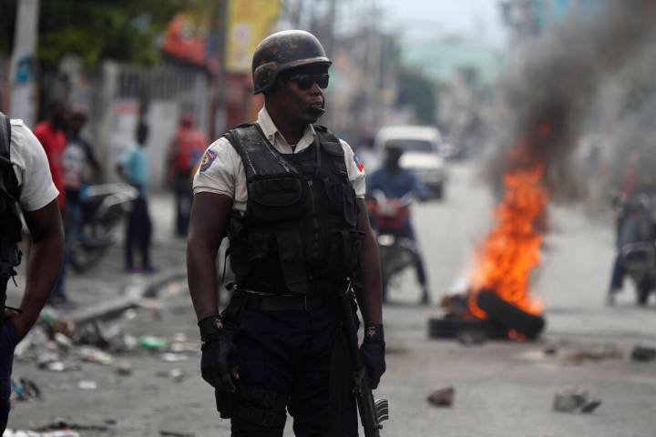 A police stands near a burning barricade set up by protesters in Port-au-Prince, Haiti, Monday, ...