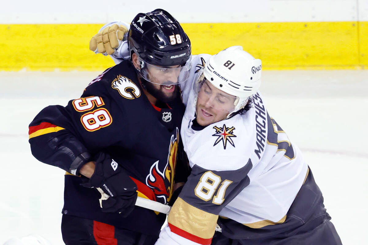 Vegas Golden Knights' Jonathan Marchessault, right, grabs Calgary Flames' Oliver Kylington duri ...