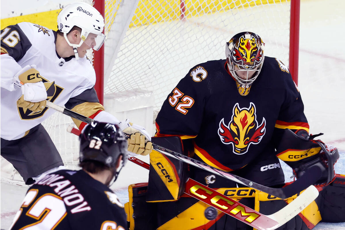 Vegas Golden Knights' Pavel Dorofeyev, left, has a shot stopped by Calgary Flames goalie Dustin ...