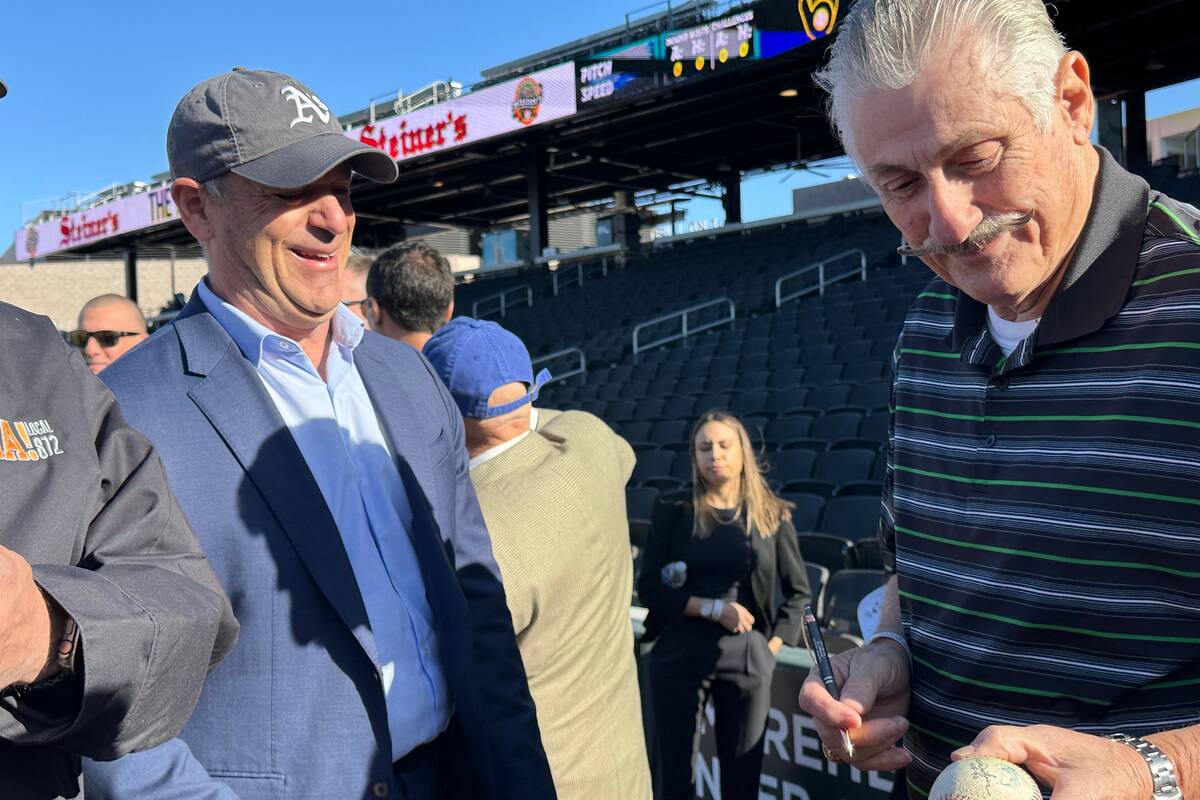 Oakland Athletics owner John Fisher (left) and A's hall of fame pitcher Rollie Fingers sign a b ...