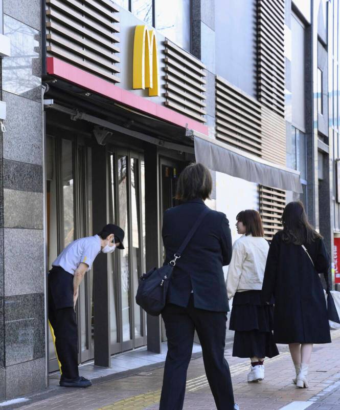 A McDonald's employee bows in front of its store amid their system outages in Tokyo, Friday, Ma ...