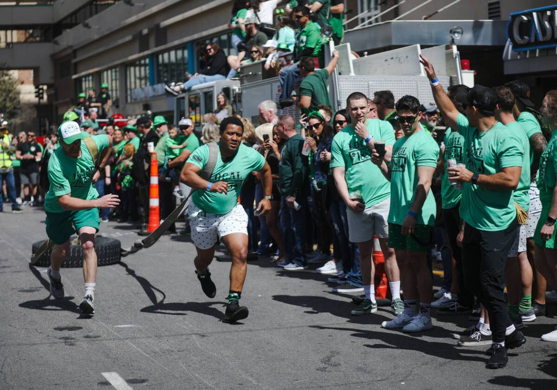 Firefighters compete in a dragging tires race at a St. Patrick’s Day event hosted by the ...