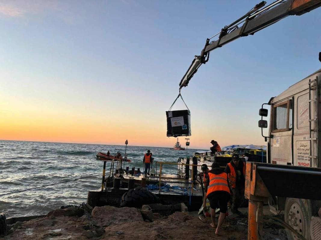 This photo provided by World Central Kitchen shows a crane unloading food packages over a makes ...