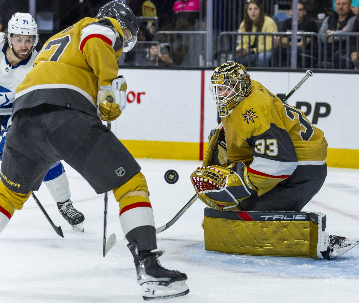 Golden Knights goaltender Adin Hill (33) looks to a puck deflected by defenseman Ben Hutton (17 ...