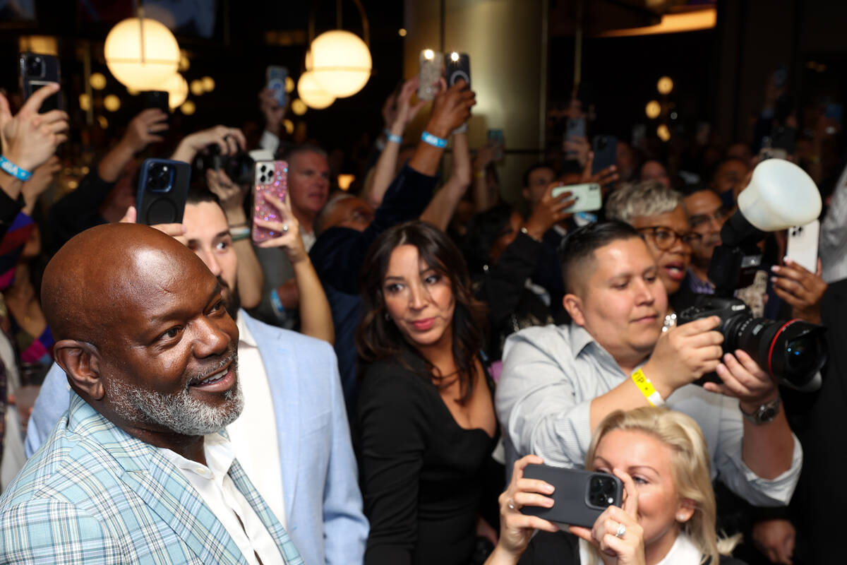 NFL legend and restaurant founder Emmitt Smith, left, admires as an artwork of his likeness in ...