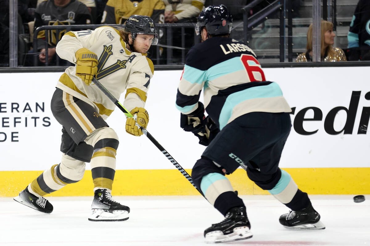 Golden Knights center William Karlsson (71) sends the puck past Kraken defenseman Adam Larsson ...