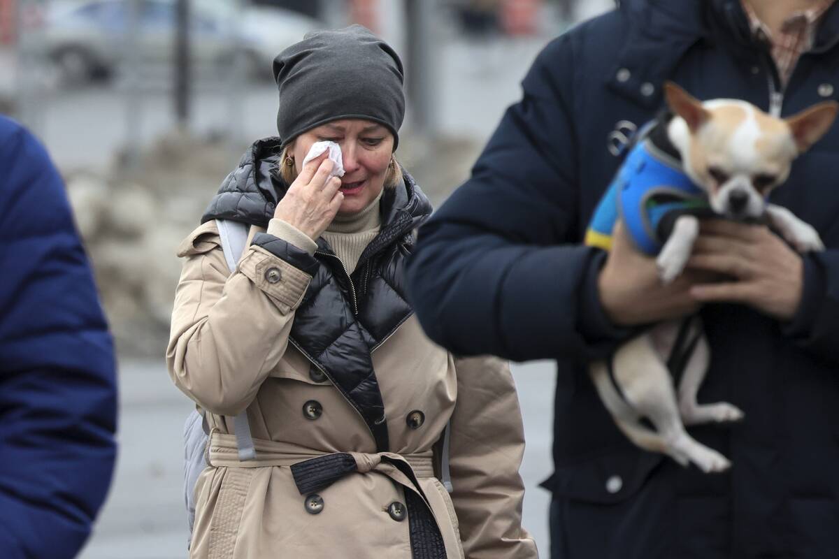 A woman reacts as she comes to place flowers at the fence next to the Crocus City Hall, on the ...