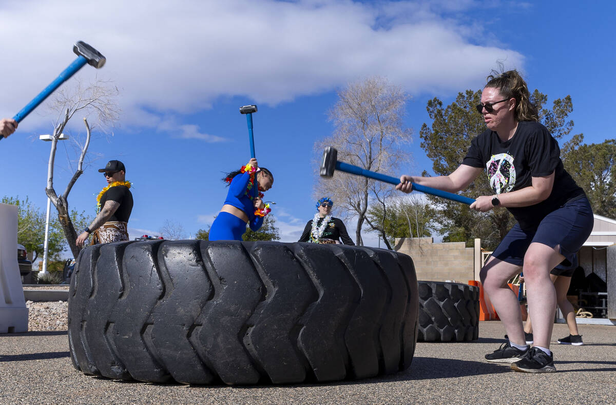 Attendees Elisa Gow, right, and Chrisjen Walker, center, join others in driving a sledge hammer ...