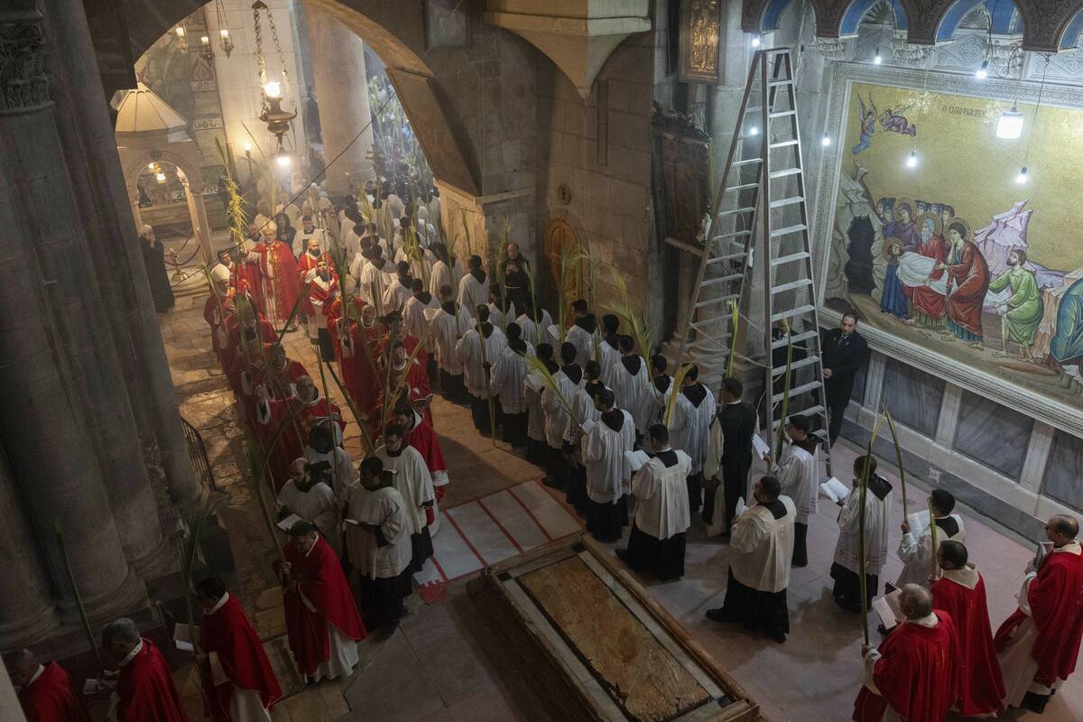 Roman Catholic clergymen carry palm fronds during the Palm Sunday procession at Church of the H ...