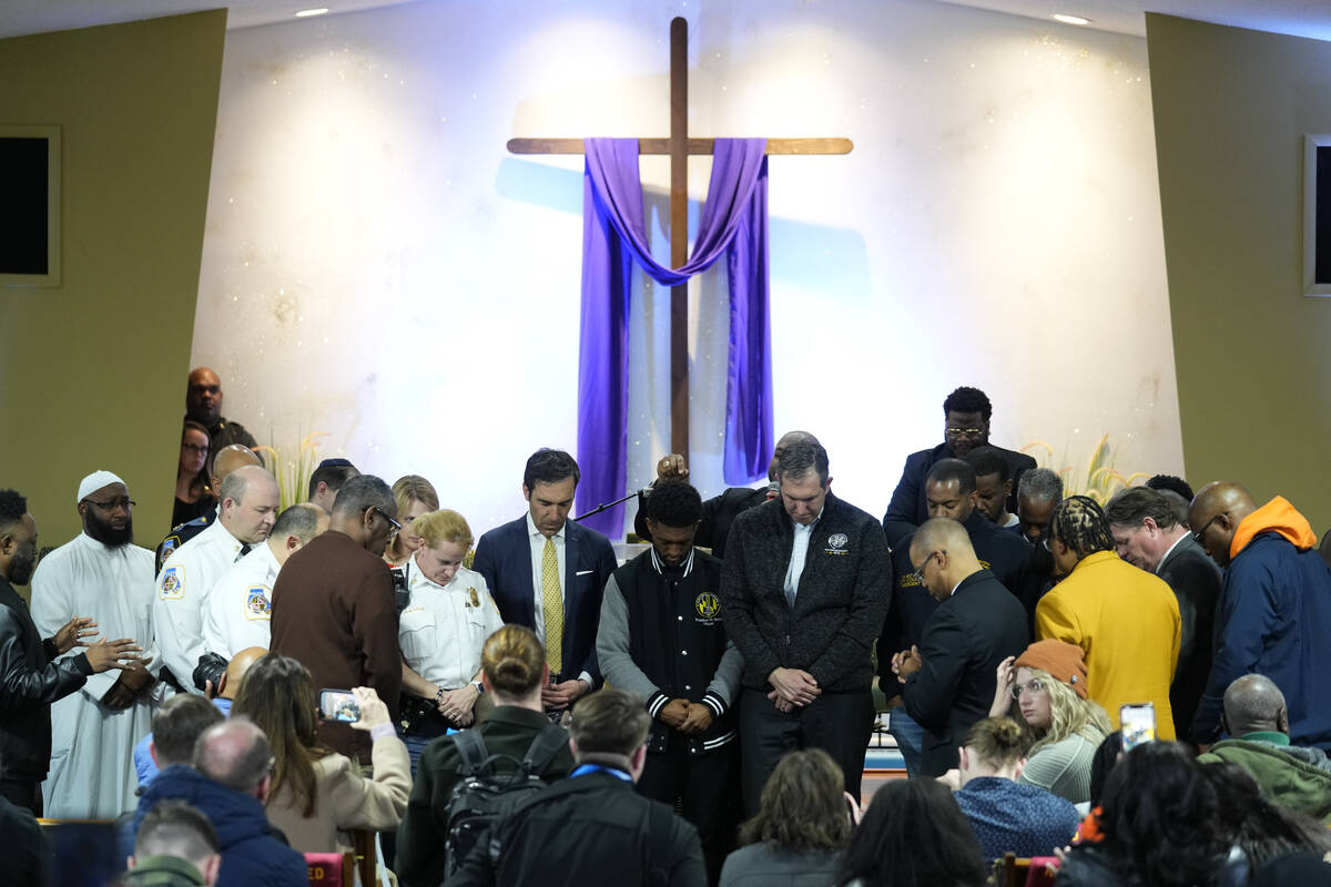 People pray for officials including Baltimore Mayor Brandon Scott, center, during a vigil near ...