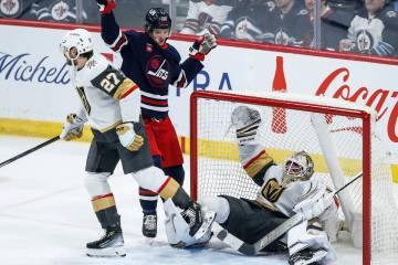 Vegas Golden Knights' Shea Theodore (27) collides with his goaltender Logan Thompson as he defe ...