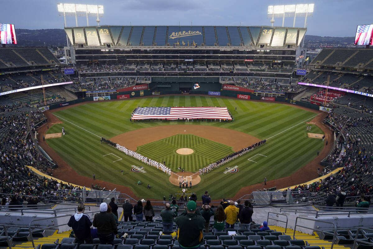 The Oakland Athletics and the Cleveland Guardians listen to the national anthem before a baseba ...