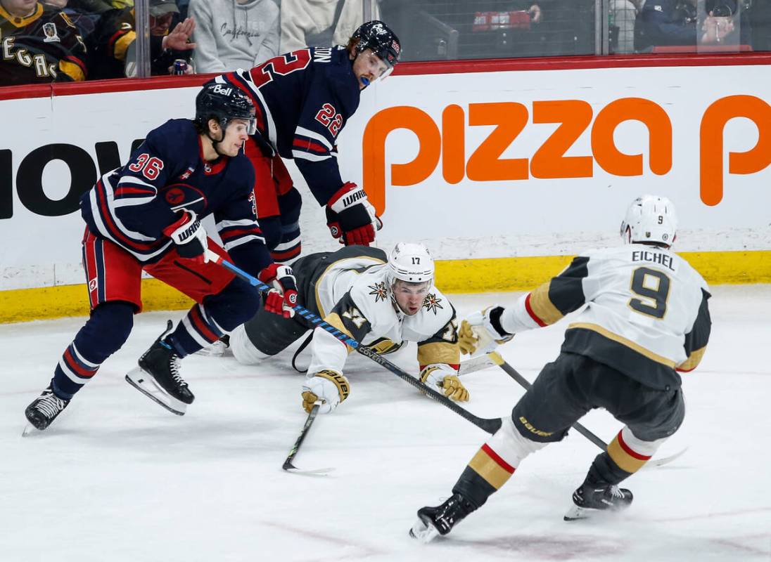 Vegas Golden Knights' Ben Hutton (17) tries to poke the puck away from Winnipeg Jets' Morgan Ba ...