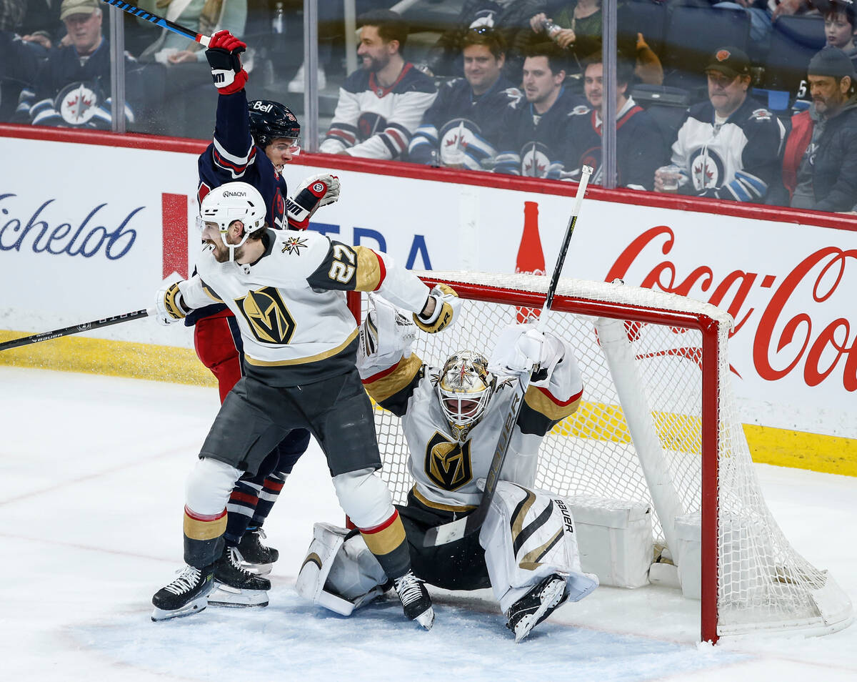 Vegas Golden Knights' Shea Theodore (27) collides with his goaltender Logan Thompson as he defe ...