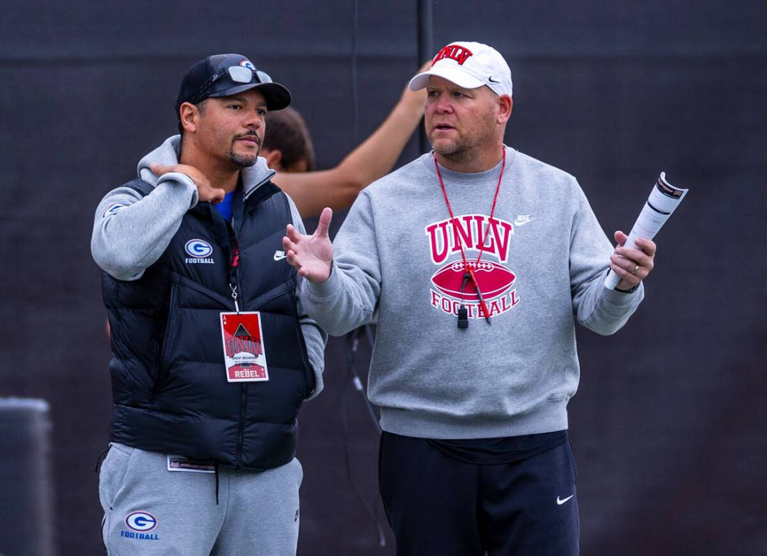 UNLV head coach Barry Odom, right, talks with Bishop Gorman head coach Brent Browner as players ...