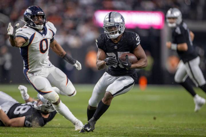 Raiders running back Zamir White (35) rushes as Denver Broncos linebacker Jonathon Cooper (0) i ...