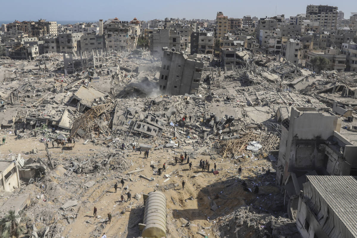 Palestinians walk through the destruction left by the Israeli air and ground offensive on the G ...