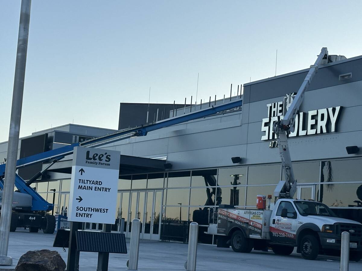 Workers update signage at Lee's Family Forum, the Henderson arena formerly named Dollar Loan Ce ...