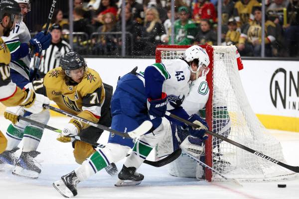 Golden Knights center William Karlsson (71) battles at the net with Canucks defenseman Quinn Hu ...