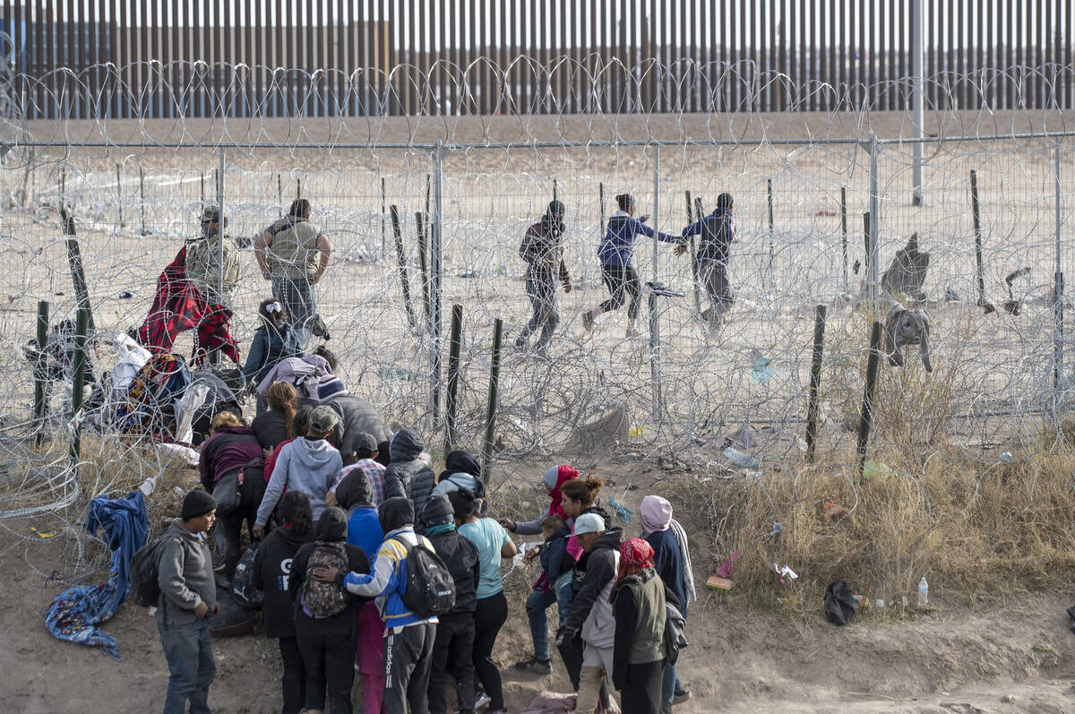 Migrants breach infrastructure set up by the Texas National Guard on the Rio Grande in El Paso, ...