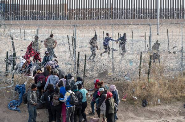 Migrants breach infrastructure set up by the Texas National Guard on the Rio Grande in El Paso, ...