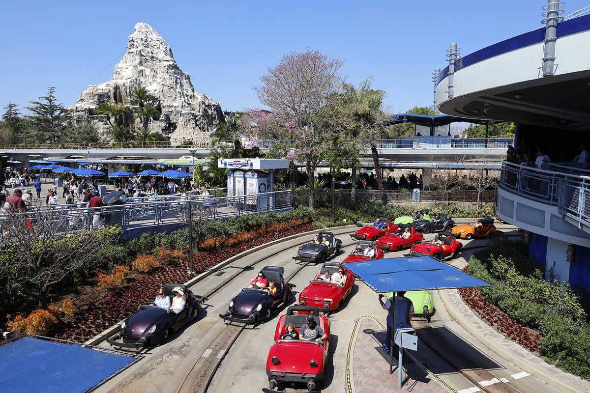 Disneyland guests wait in traffic near the exit to Autopia, with the Matterhorn Bobsleds ride i ...