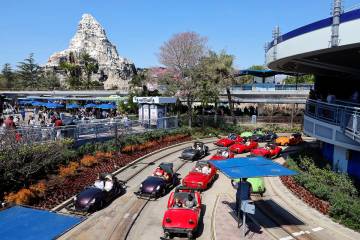 Disneyland guests wait in traffic near the exit to Autopia, with the Matterhorn Bobsleds ride i ...