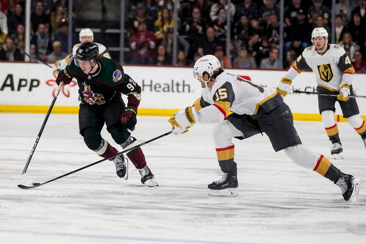 Arizona Coyotes center Logan Cooley (92) corrals the puck in front of Vegas Golden Knights defe ...