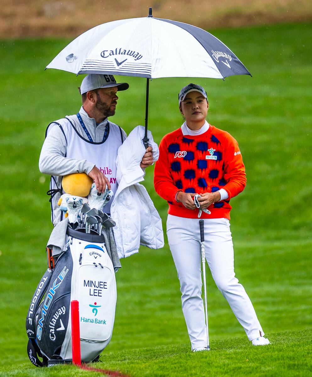 Minjee Lee is covered with an umbrella by caddie Rance De Grussa on the green at hole #15 durin ...
