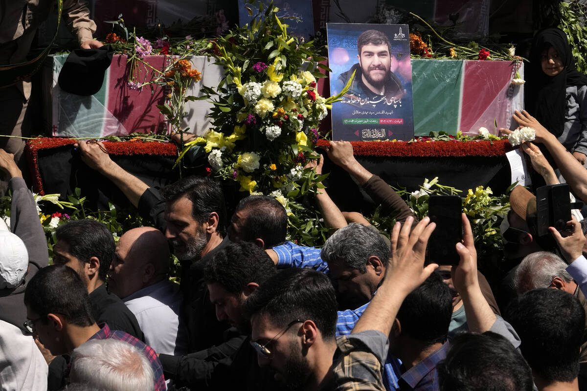 Iranian mourners try to touch the flag-draped coffins of Revolutionary Guard members killed in ...