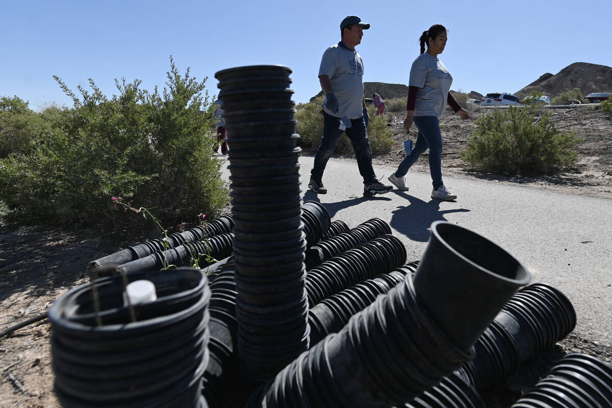 Volunteers walk past stacks of empty plant containers during the Las Vegas Wash Coordination Co ...
