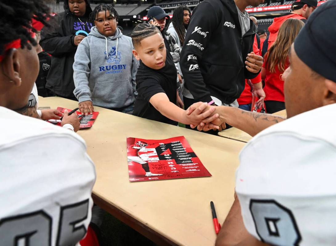 Maddox Moore shakes UNLV wide receiver Timothy Conerly’s hand while collecting autograph ...