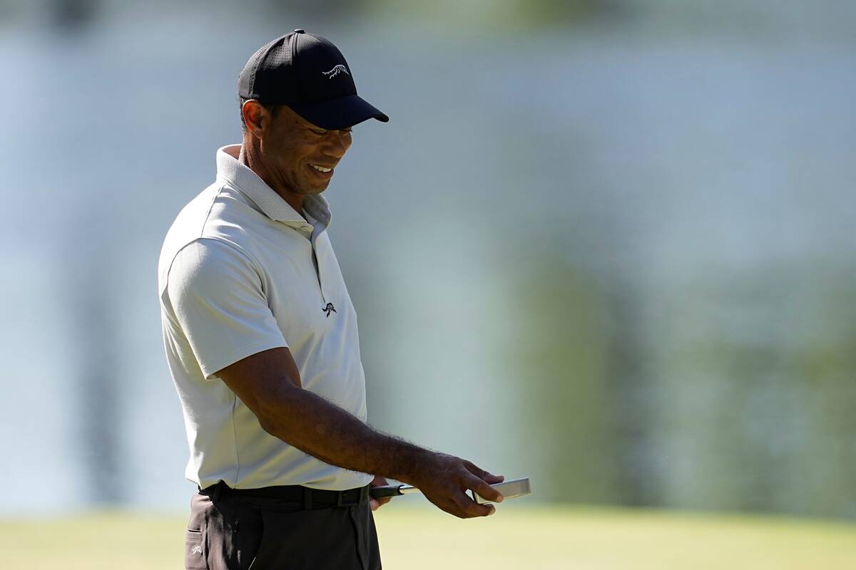 Tiger Woods looks at his putter on the 16th green during a practice round in preparation for th ...