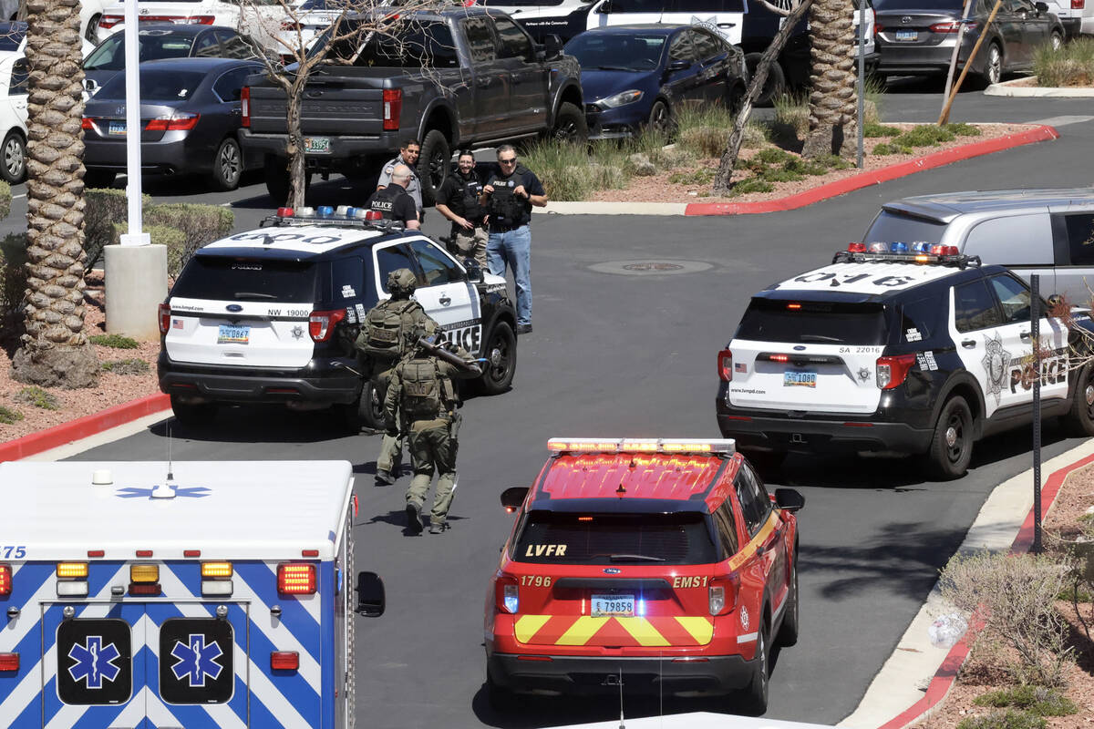 Las Vegas police with a battering ram and crow bar run toward City National Bank Building in Su ...