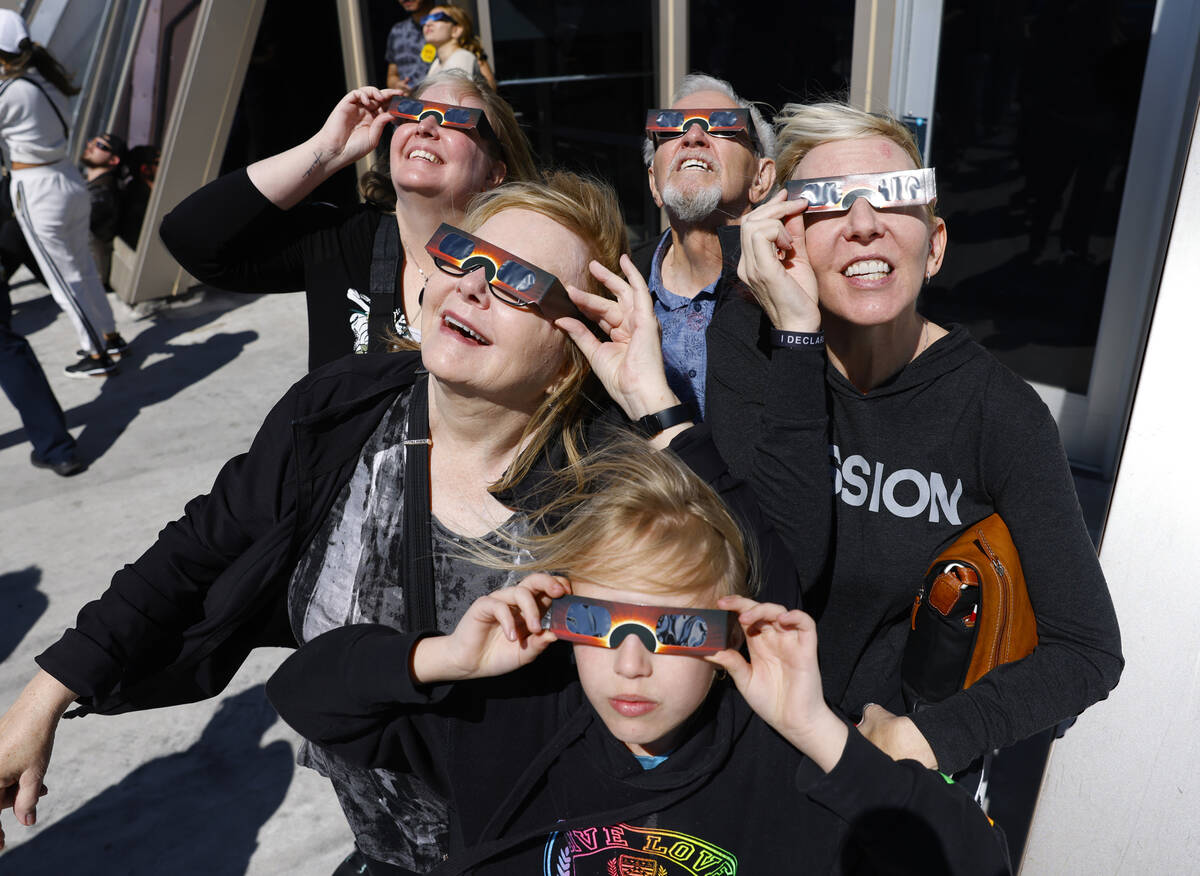 Sandra Callies, center left, and her husband, Gerard, center back, watch a partial solar eclips ...